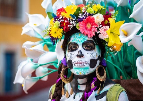 woman with painted skeleton face and flower crown for day of the dead celebration