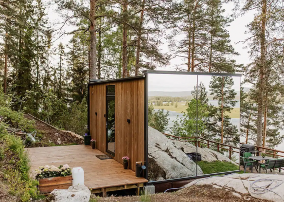 Mirrored walled cabin surrounded by tall pine trees